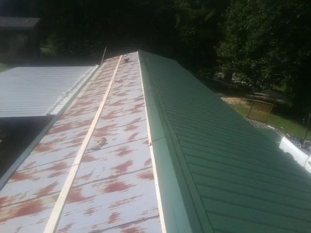 Old rusted panels beside newly installed green metal roofing — Wind Damage Roof Repair by Roofing Brothers in Wise