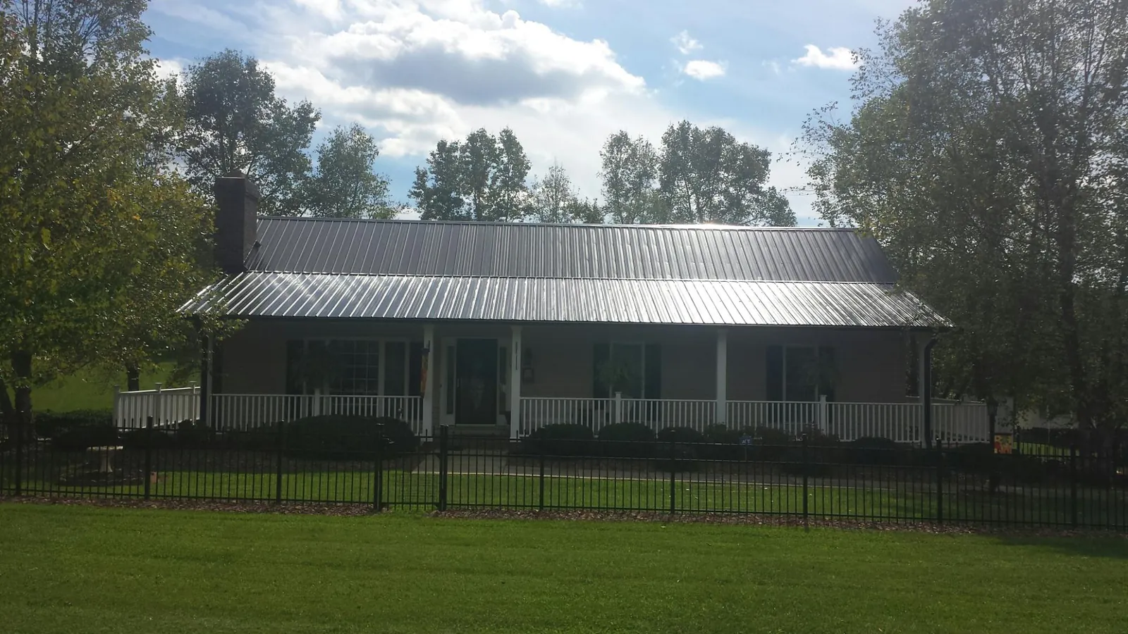 Gray metal roof on a brick ranch with a full width front porch — Gutter Guard Installation work by our crew in Wise