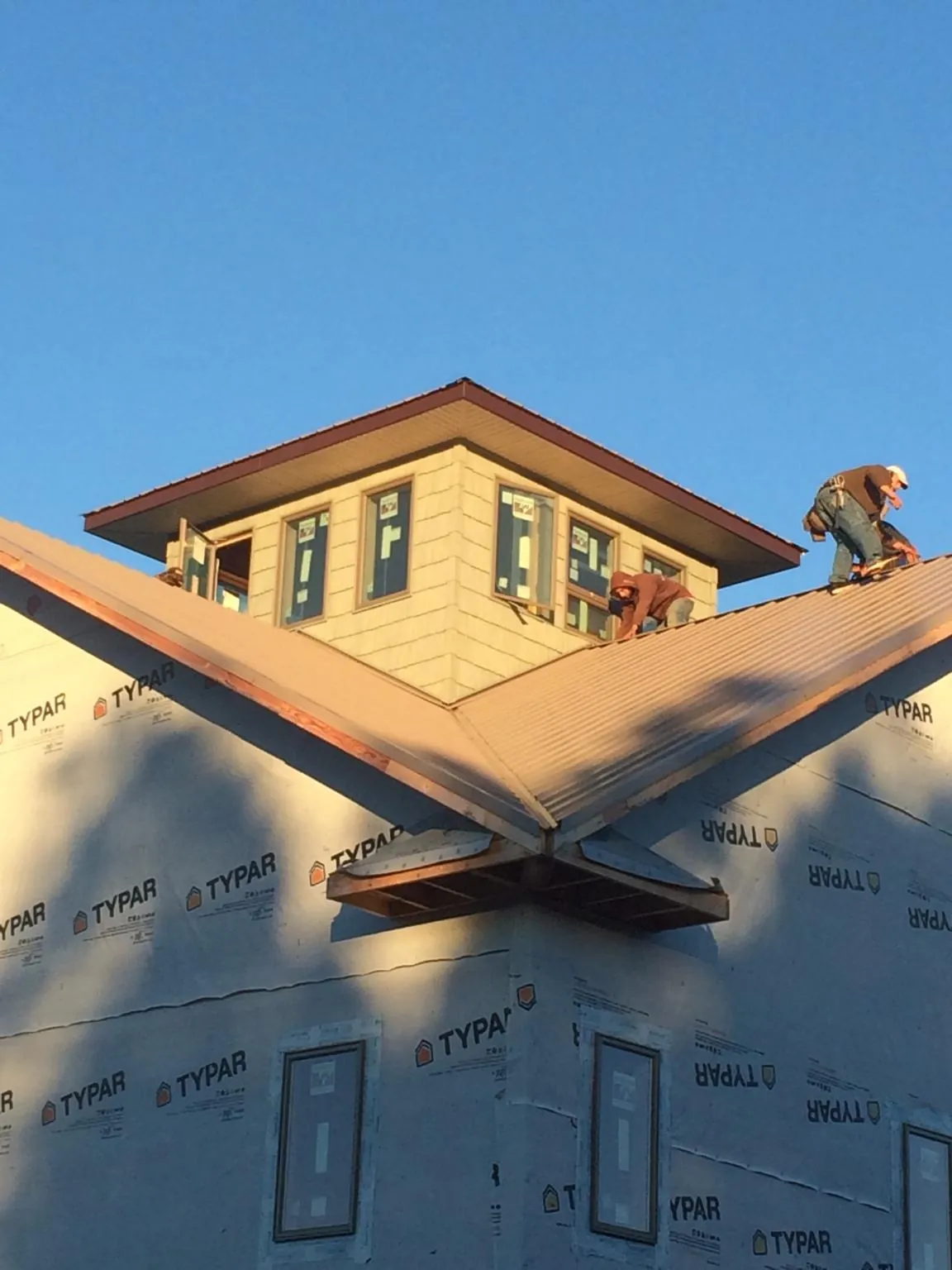 Roofers working around a rooftop cupola on a new metal roof at sunset — Roof Waterproofing in Wise by Roofing Brothers